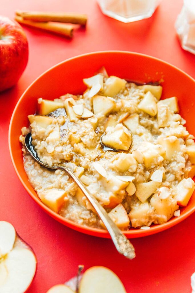 An orange bowl filled with apple cinnamon oatmeal