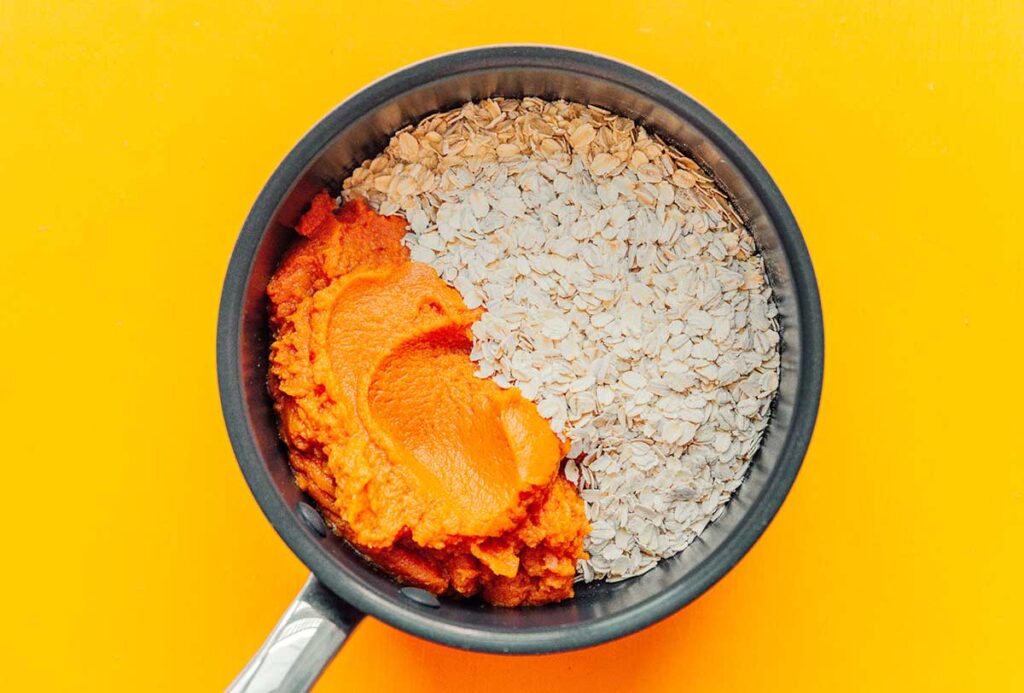 A pot filled with uncooked rolled oats and pumpkin puree