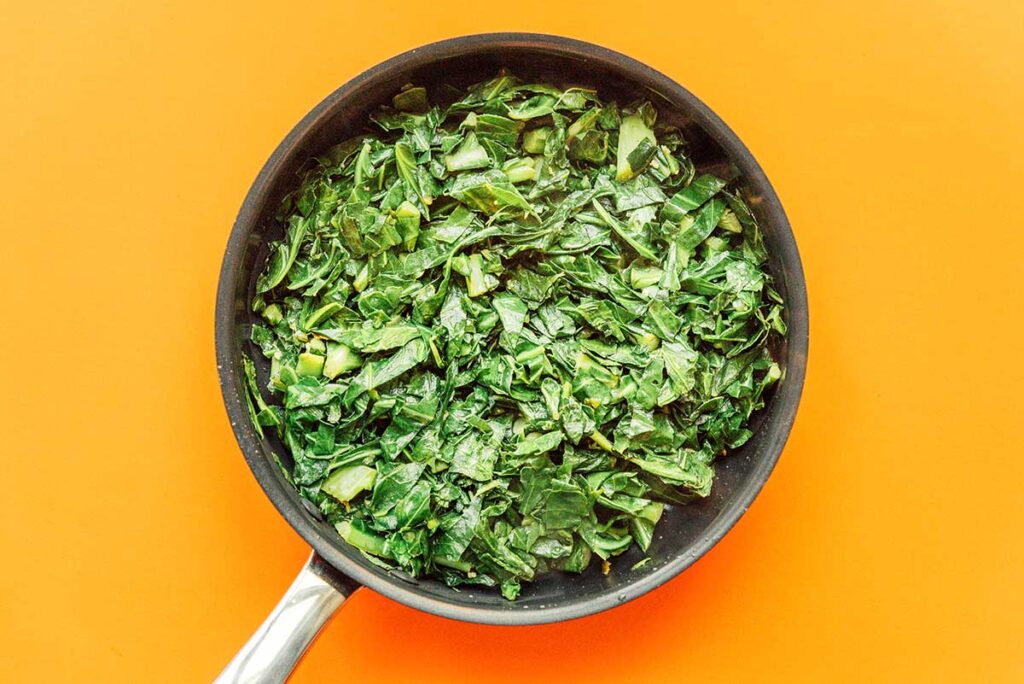A pan filled with freshly sautéed chopped collard greens