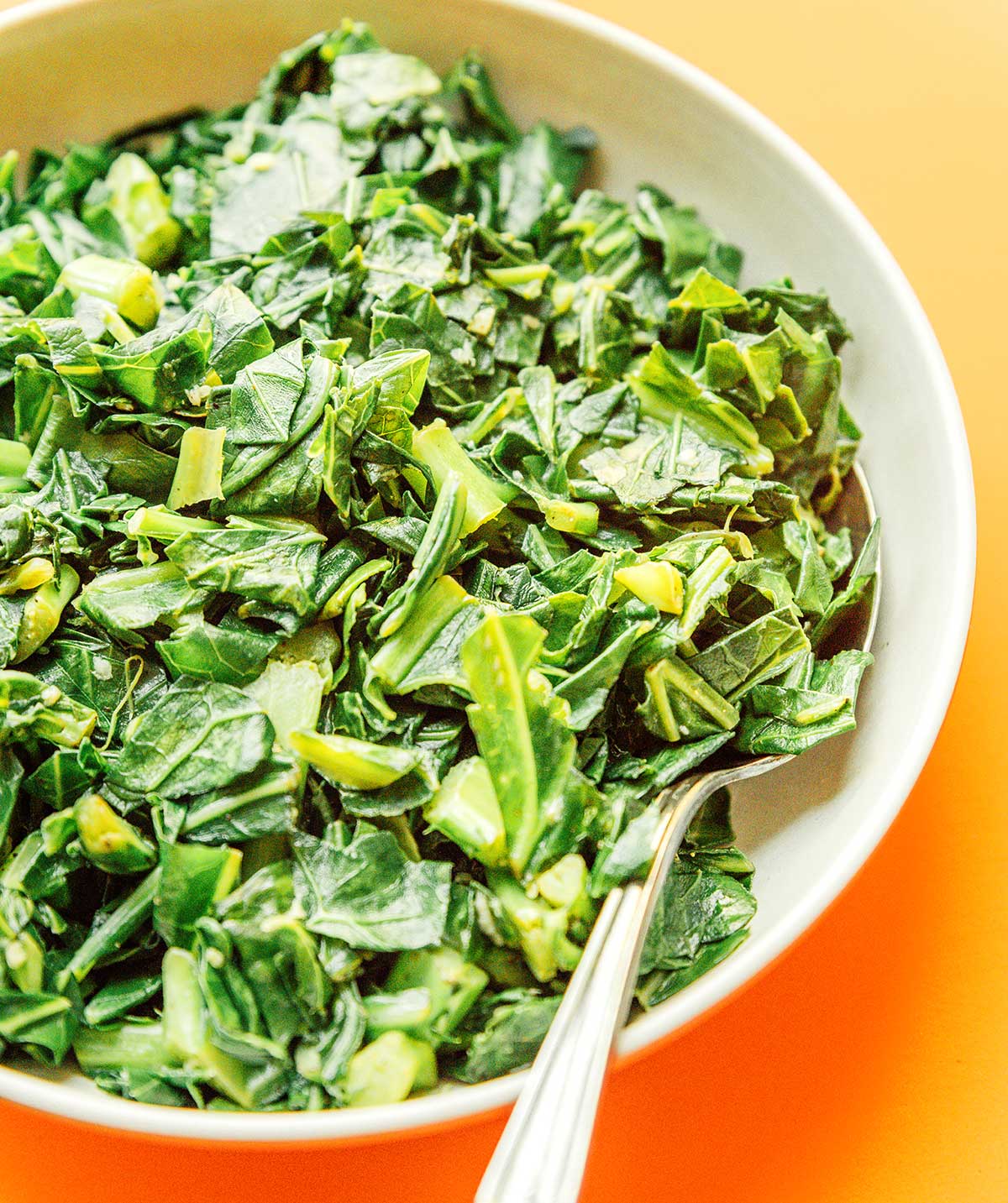 A white bowl filled with chopped and sautéed collard greens