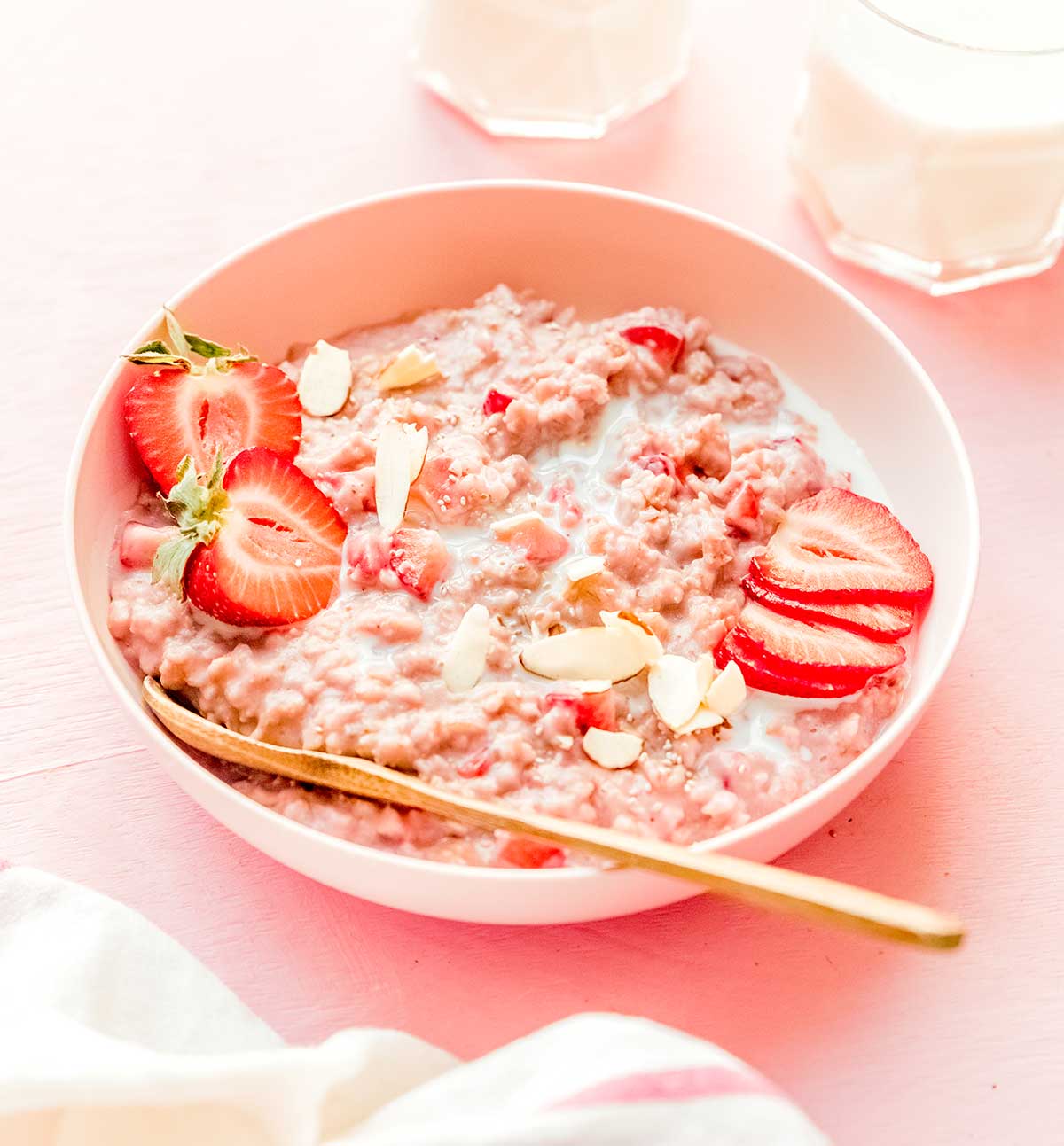 A bowl of strawberry oats topped with strawberry slices and halves and almond slivers