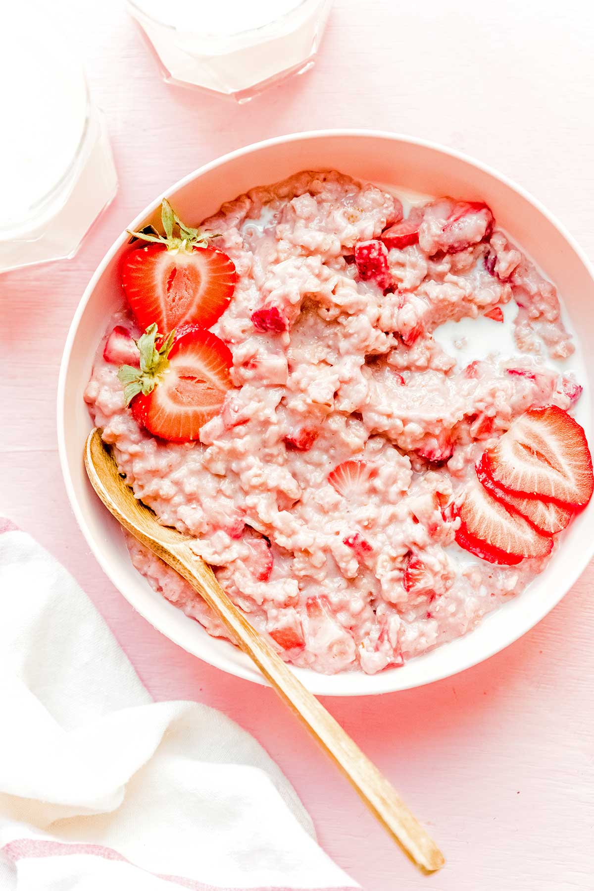 A bowl of healthy strawberry oatmeal topped with strawberry slices and halves and almond slivers