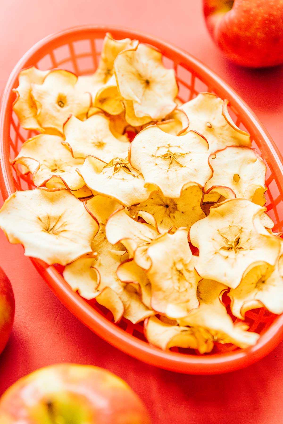 A red basket filled with oven baked apple chips