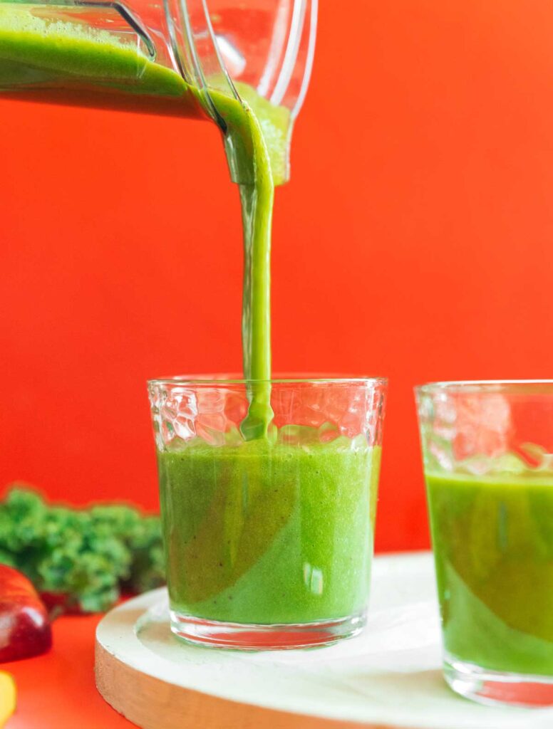 Pouring kale and apple smoothie from a blender into a glass