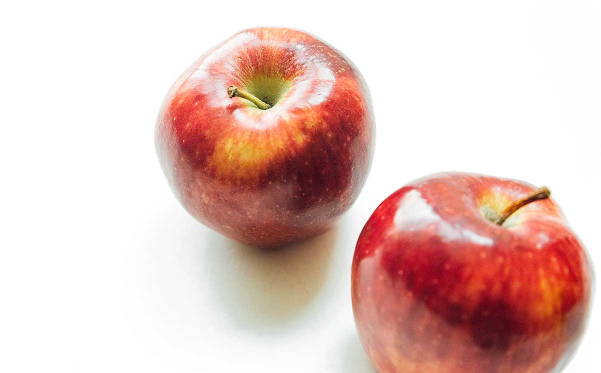Two pink lady apples on a white background