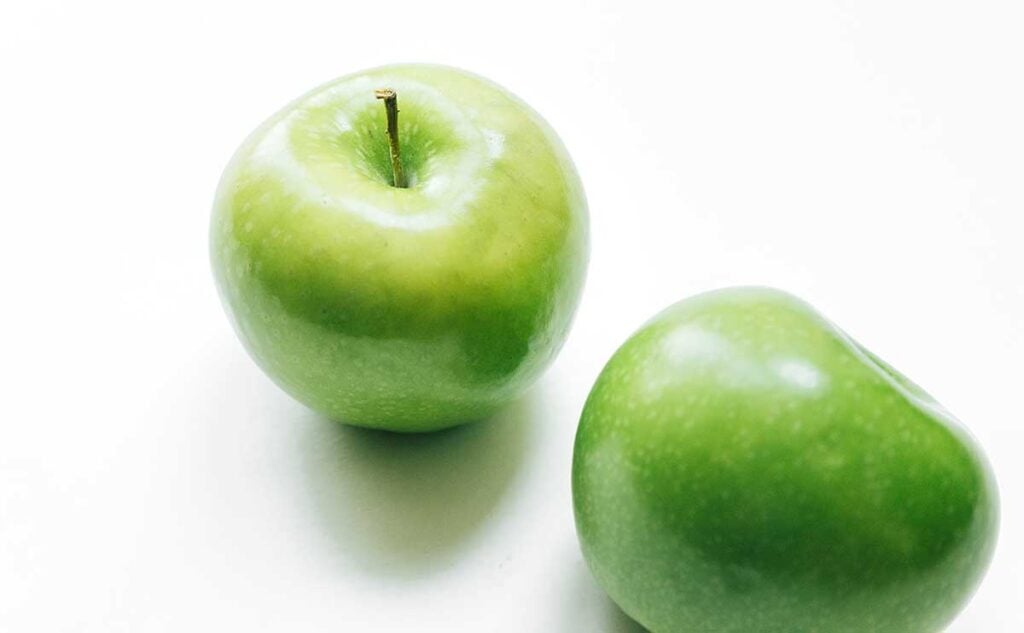 Two granny smith apples on a white background