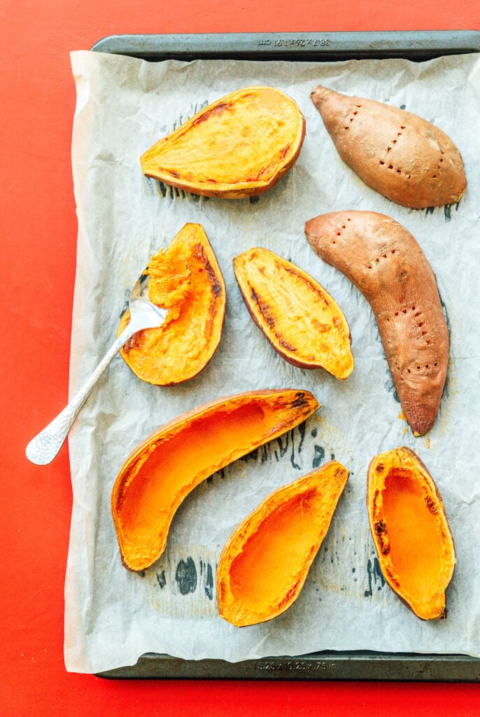 A fork removing the flesh from cooked sweet potato halves