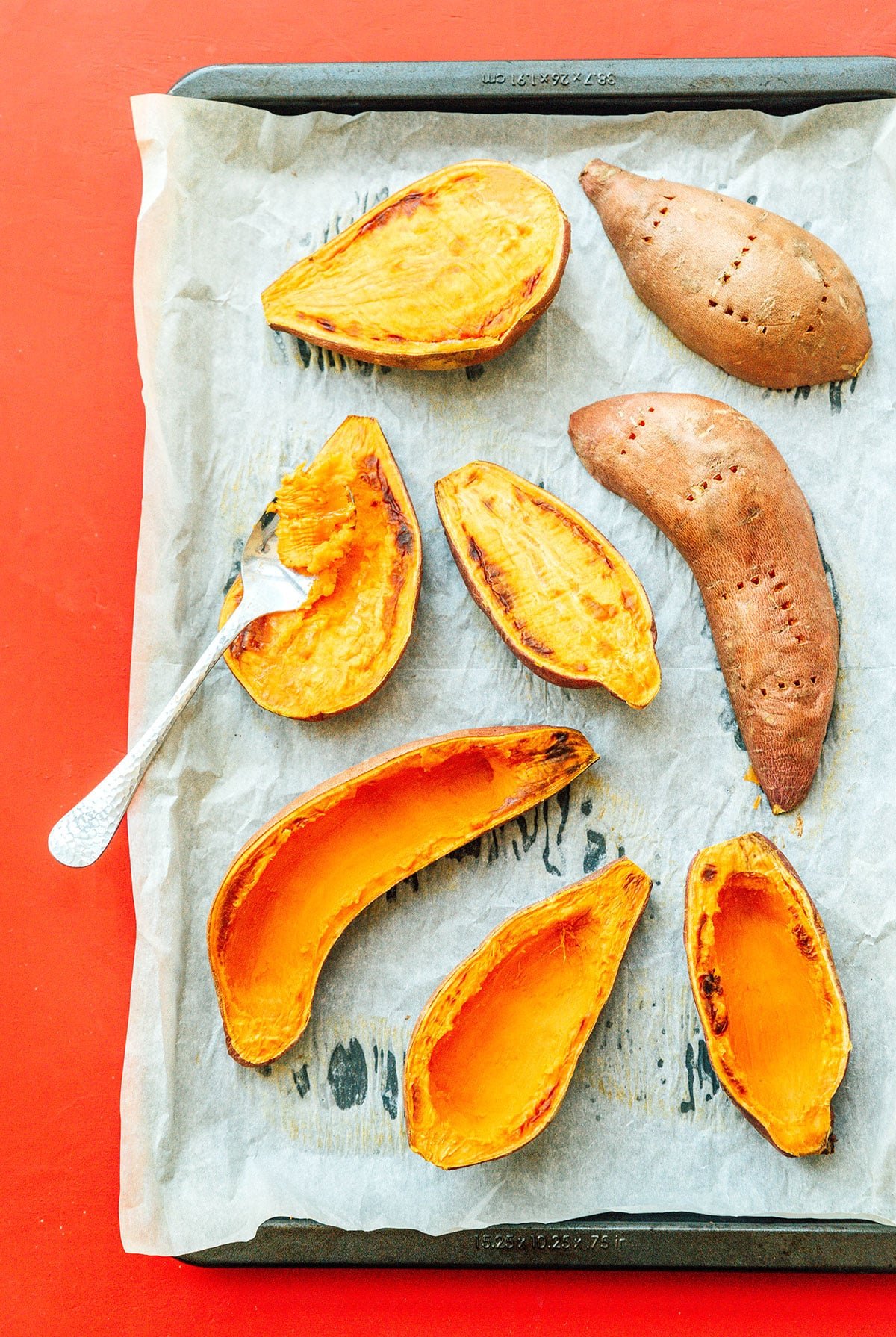 A fork removing the flesh from cooked sweet potato halves
