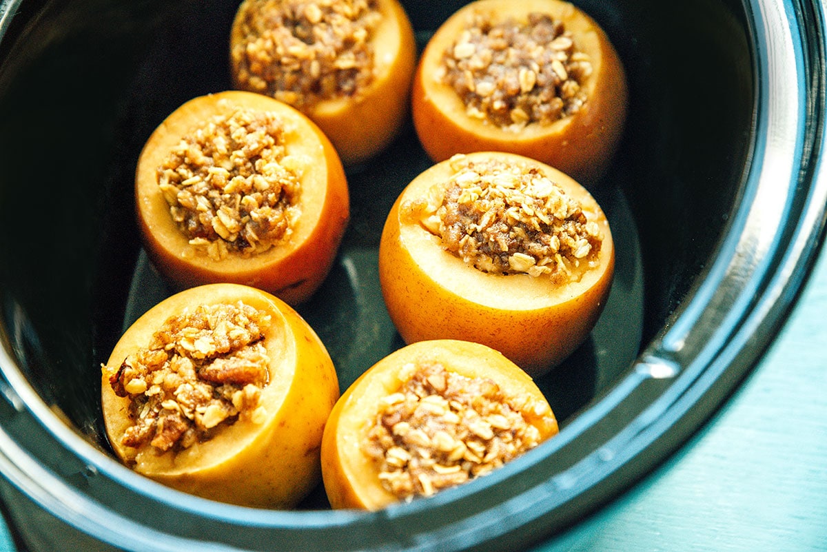 A slow cooker filled with 6 stuffed apples