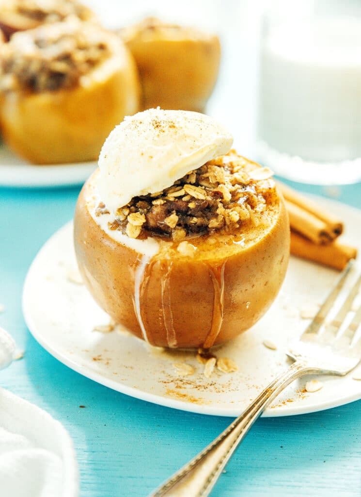 A slow cooker stuffed apple topped with a dollop of ice cream and sprinkled with cinnamon