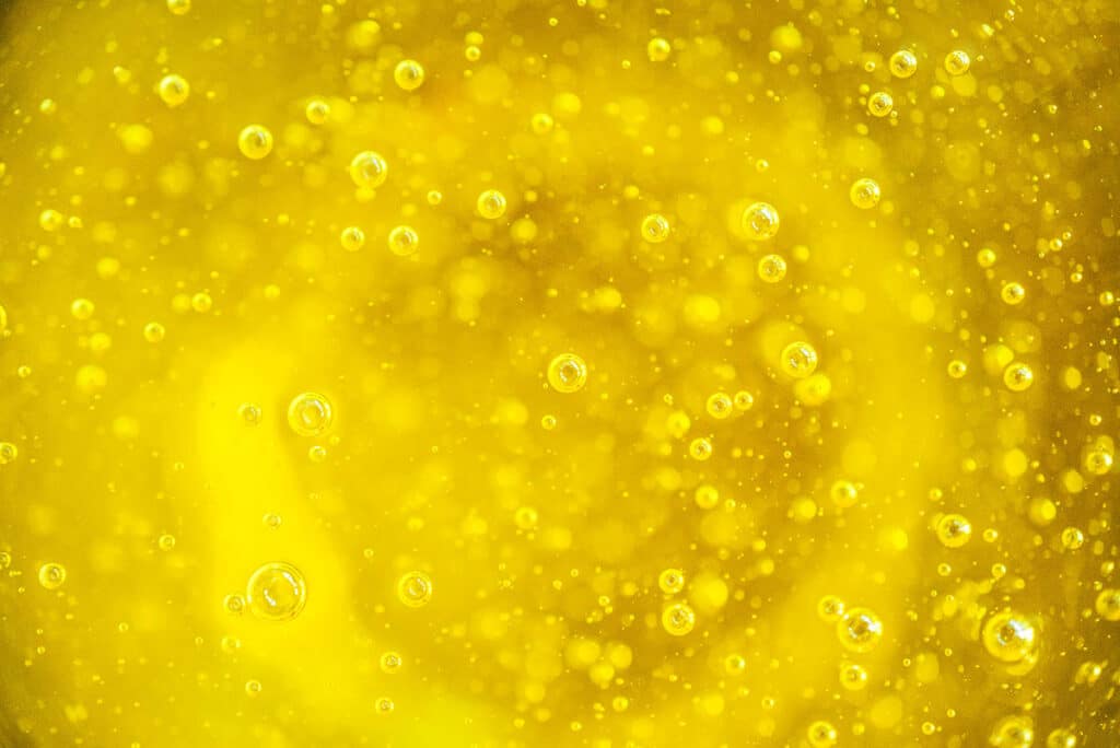 A close up view detailing the color and bubbles in olive oil