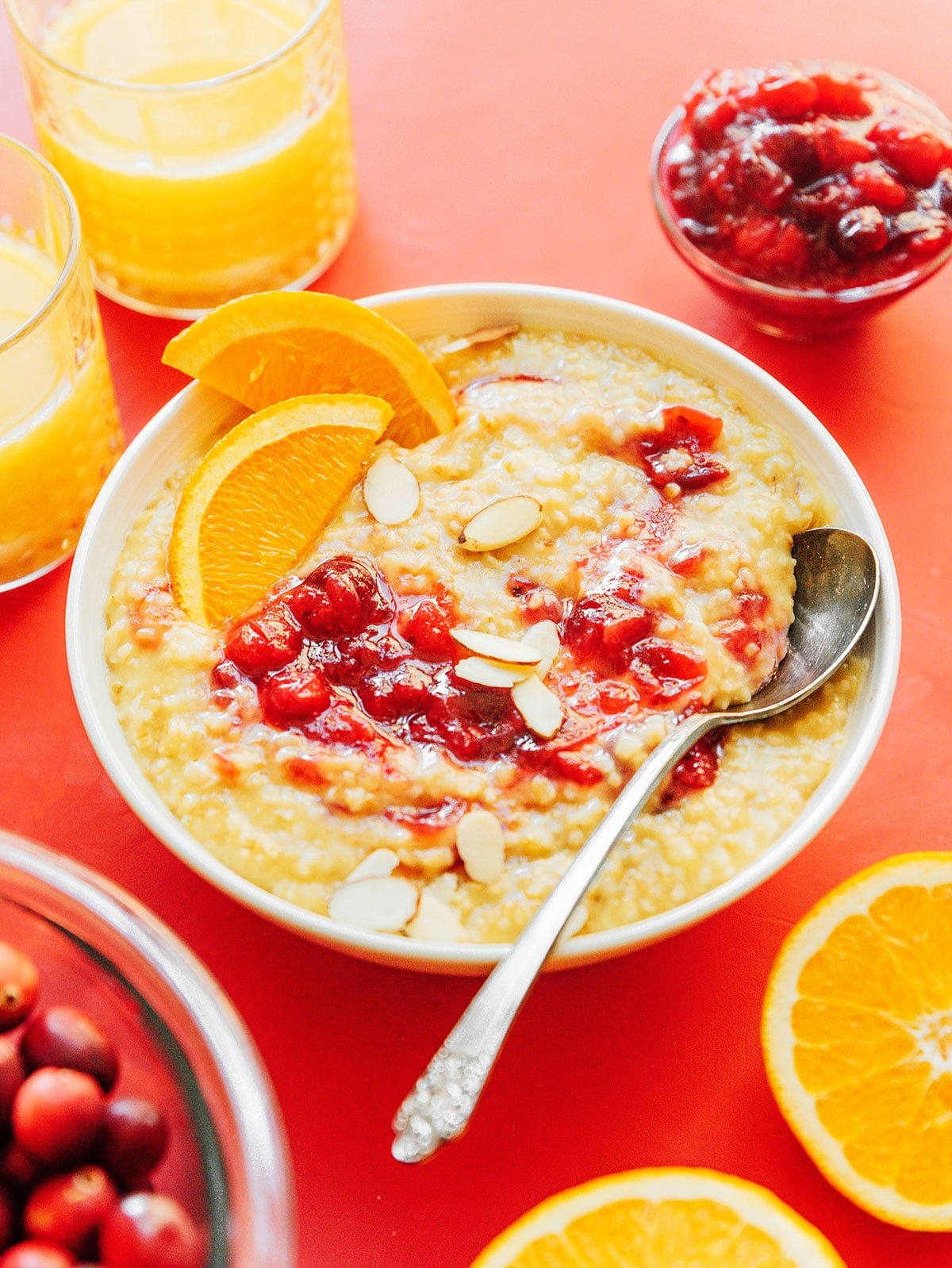 A white bowl filled with cranberry orange oatmeal garnished with sliced almonds and orange slices