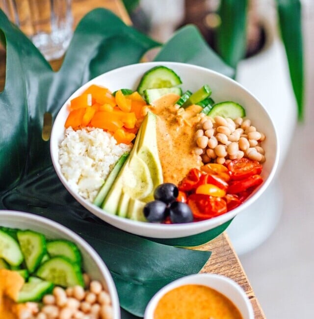 A bowl of mediterranean vegetables with avocado, chickpeas, tomatoes, and olives