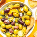 Olives in a bowl on an orange background.