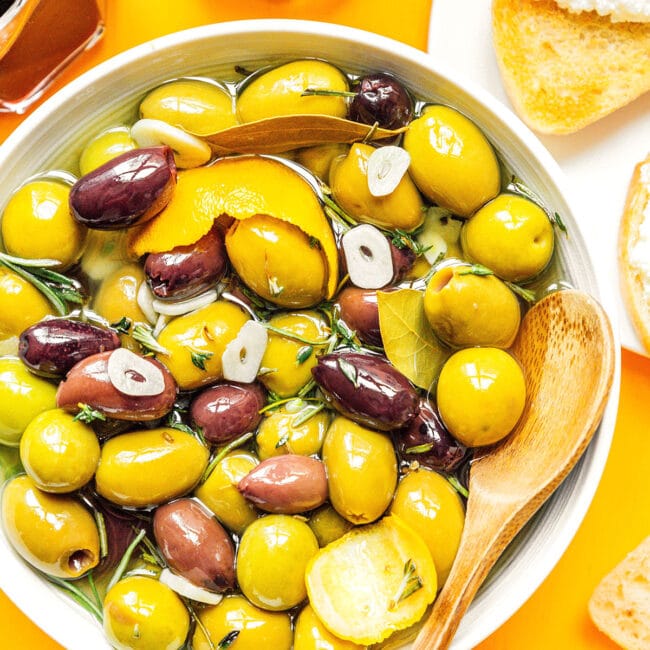 Olives in a bowl on an orange background.