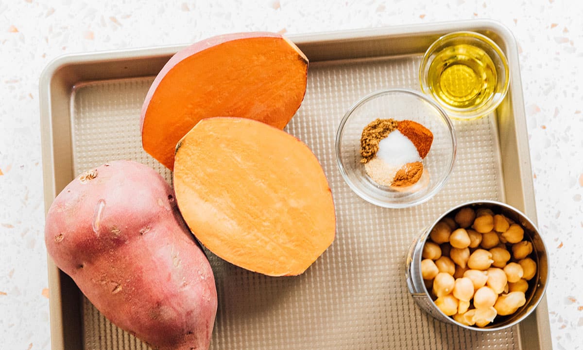Sweet potatoes and chickpeas on a baking sheet.