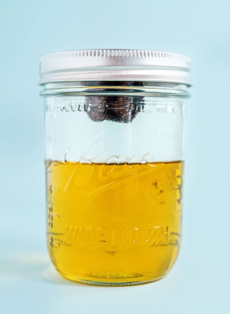 A mason jar filled 2/3 of the way with olive oil with a black truffle nailed to the lid of the jar