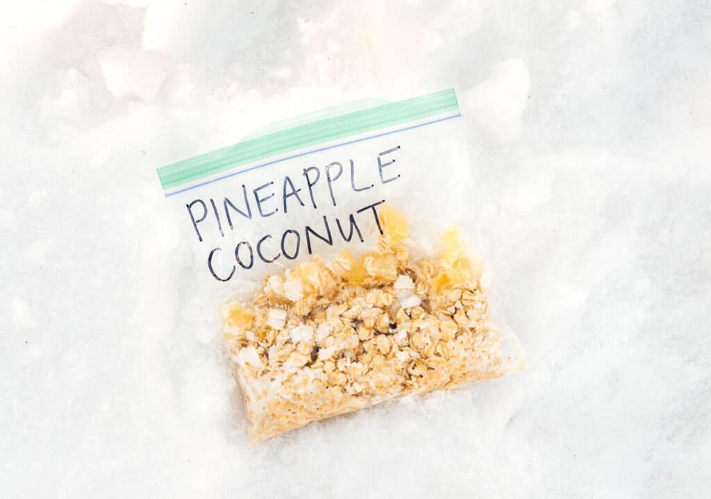 An on-the-go oatmeal pouch filled with rolled oats, milk, shredded coconut, and dried pineapple