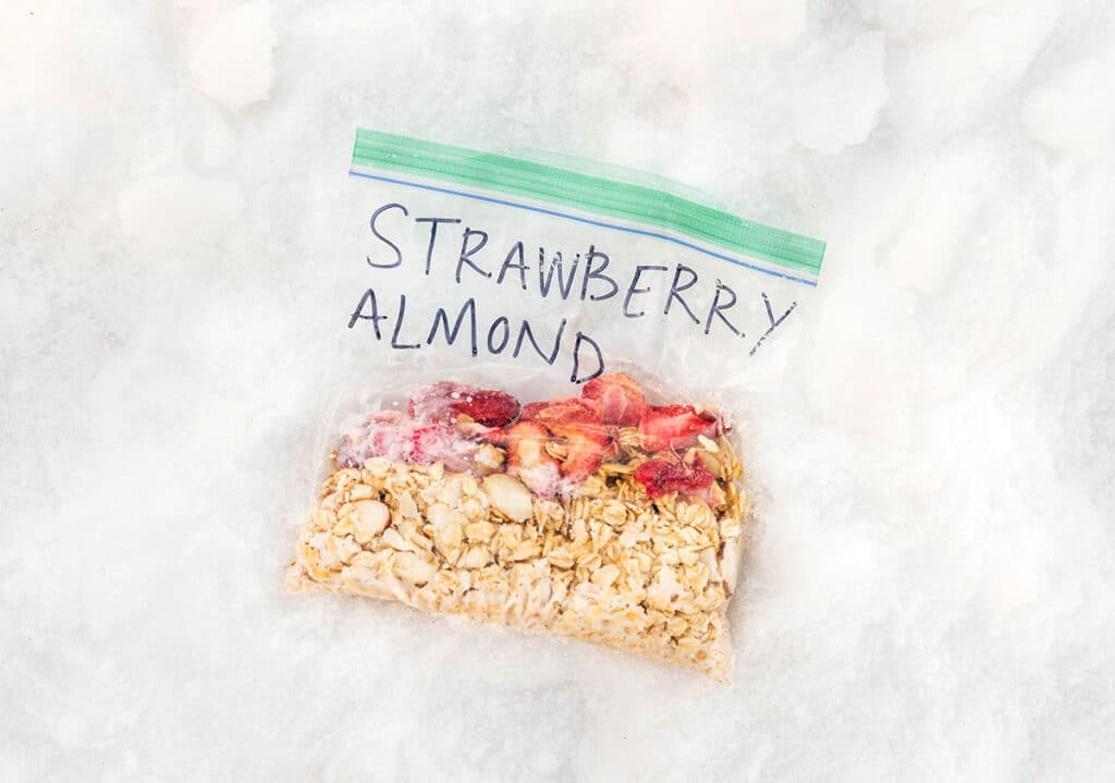 An on-the-go oatmeal pouch filled with rolled oats, milk, sliced almonds, and dried strawberries