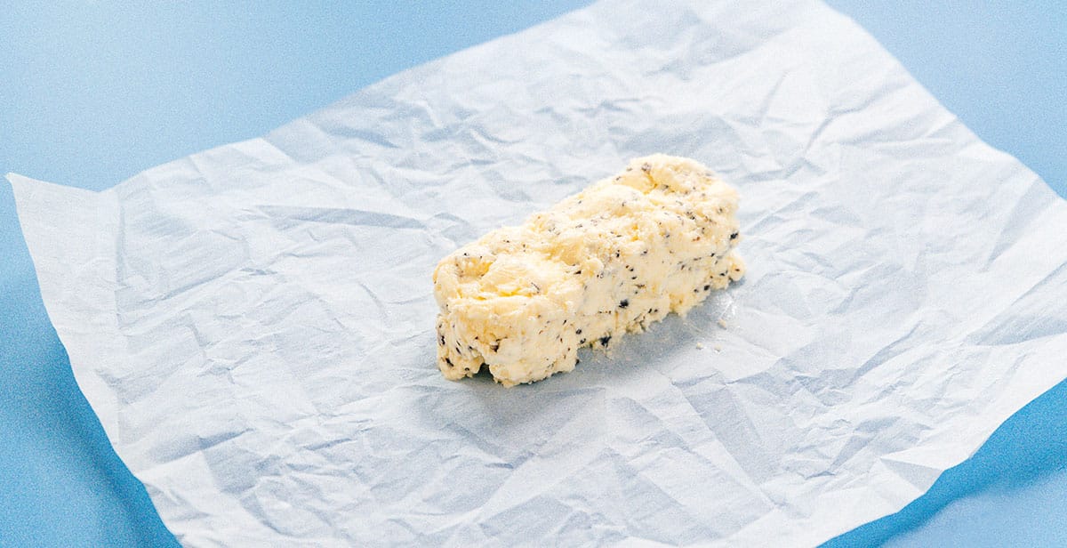 A roll of homemade truffle butter sitting on top of a piece of parchment paper