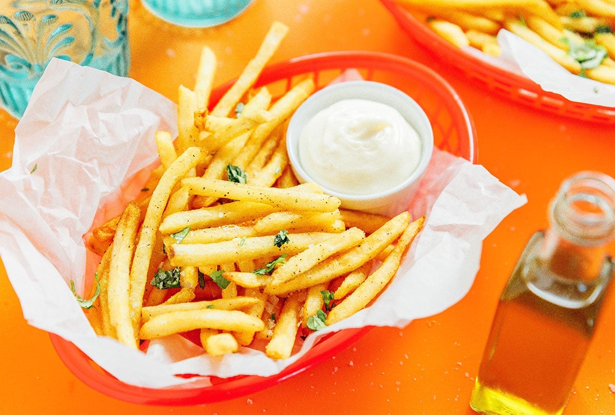 A red basket filled with truffle fries and a small container of dipping sauce