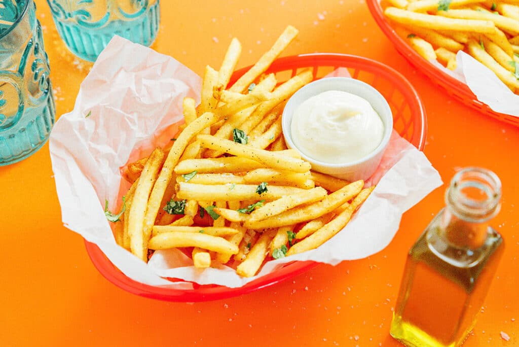 A red basket filled with truffle fries and a small container of dipping sauce