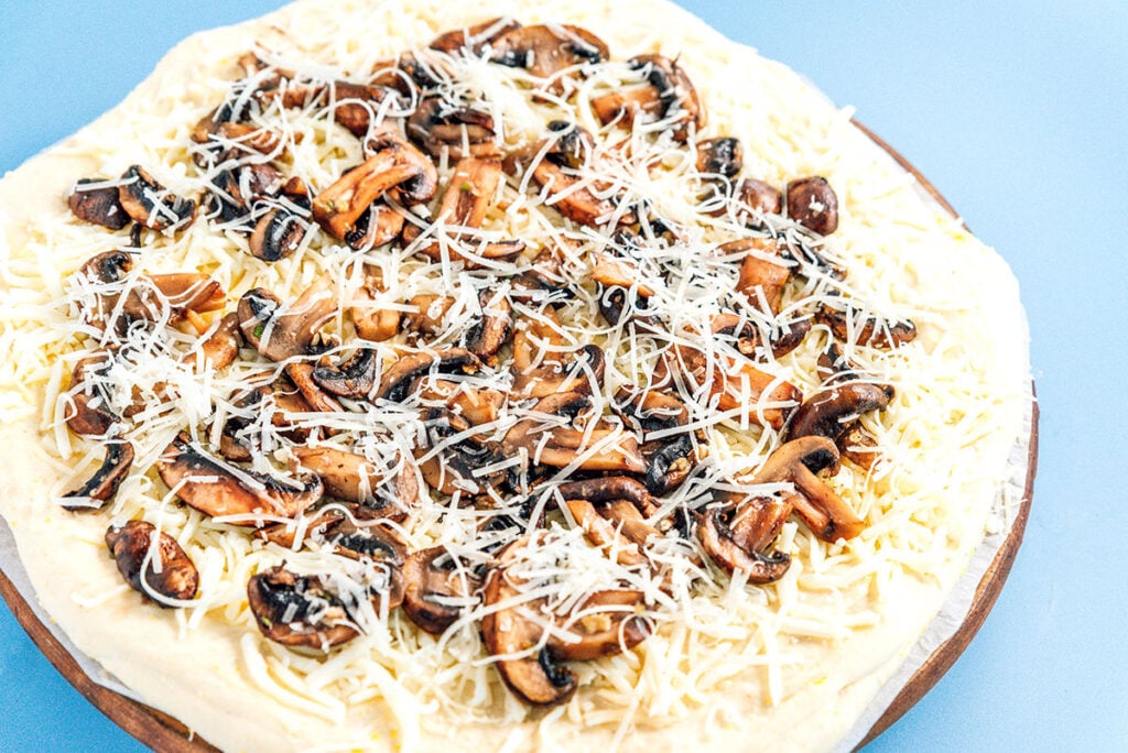 An assembled and uncooked fresh truffle pizza on top of a pizza stone