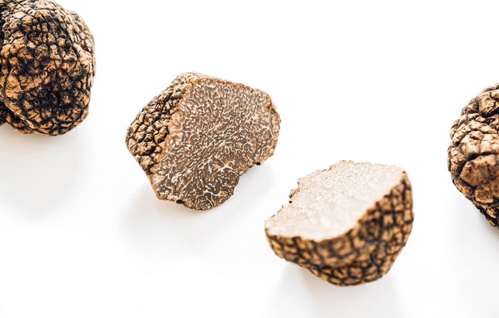 A truffle sliced in half with a whole truffle on either side