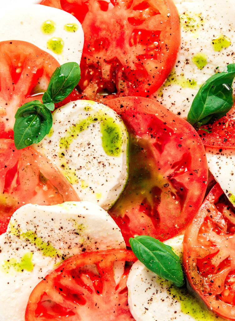 An up close view of tomato and mozzarella slices coated in a basil oil drizzle