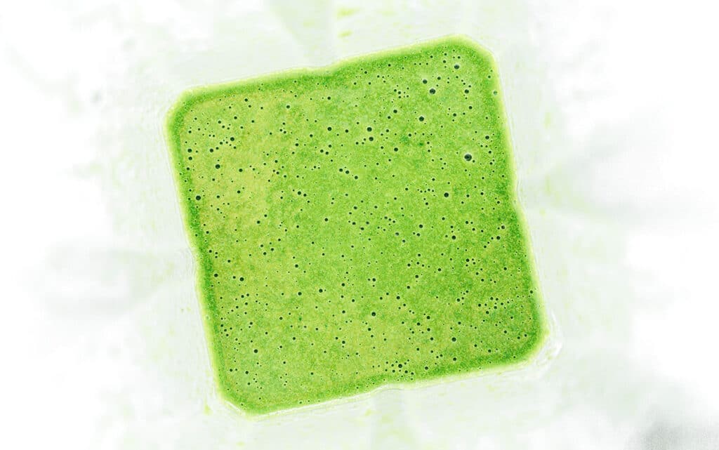 A blender filled with freshly mixed basil oil