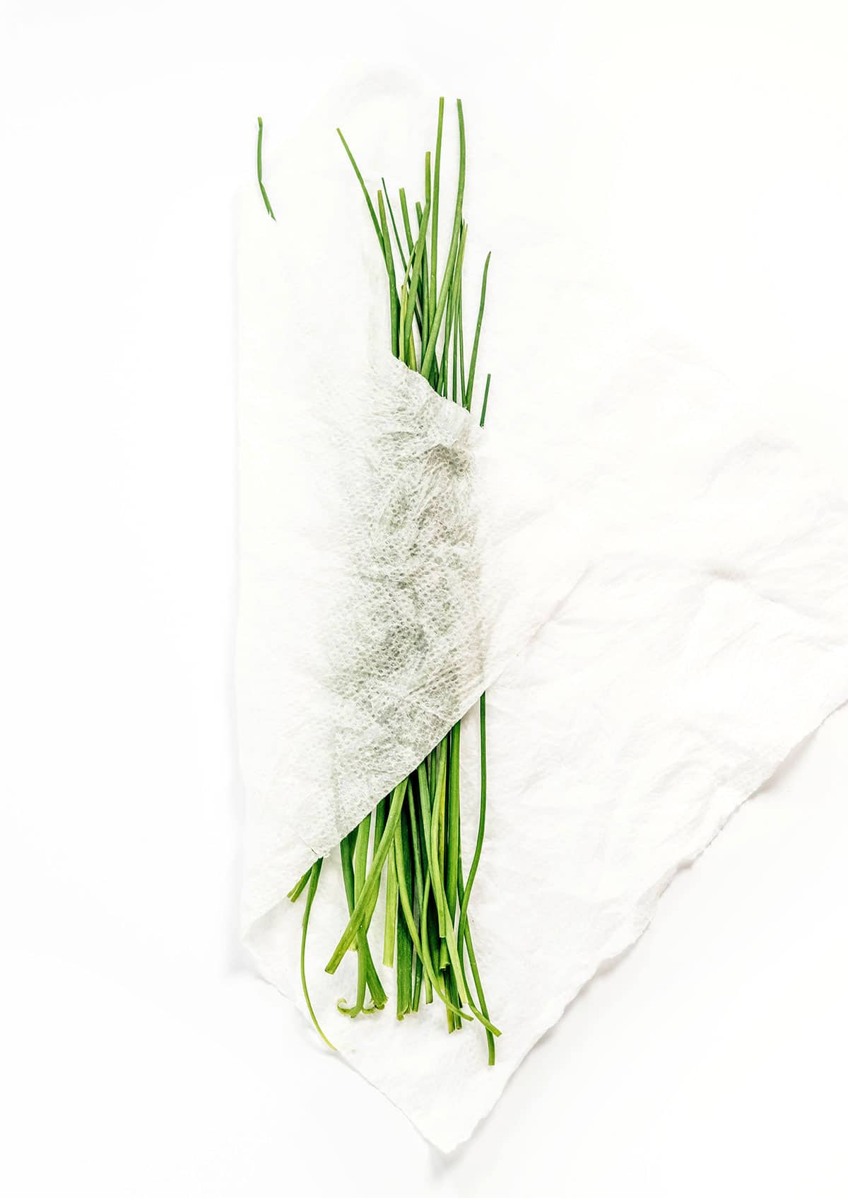 A bunch of chives wrapped in a damp paper towel
