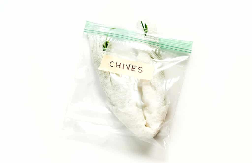 Chives wrapped in a damp paper towel and placed in a sandwich baggie