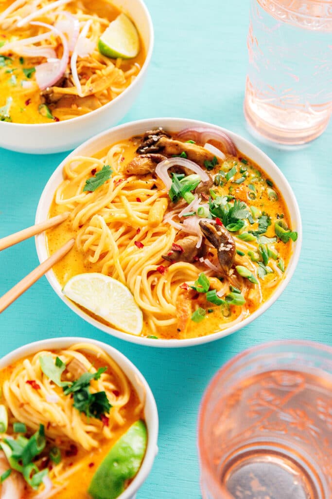 A white bowl filled with vegan khao soi with chop sticks resting inside