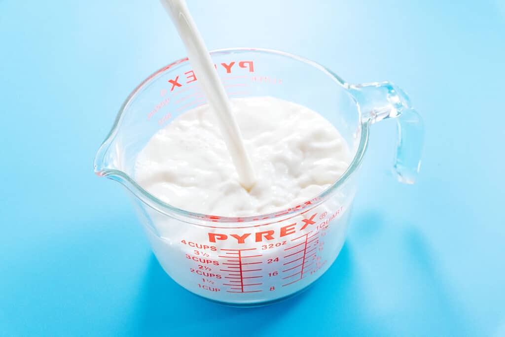 Pouring milk into a Pyrex ounce measuring cup