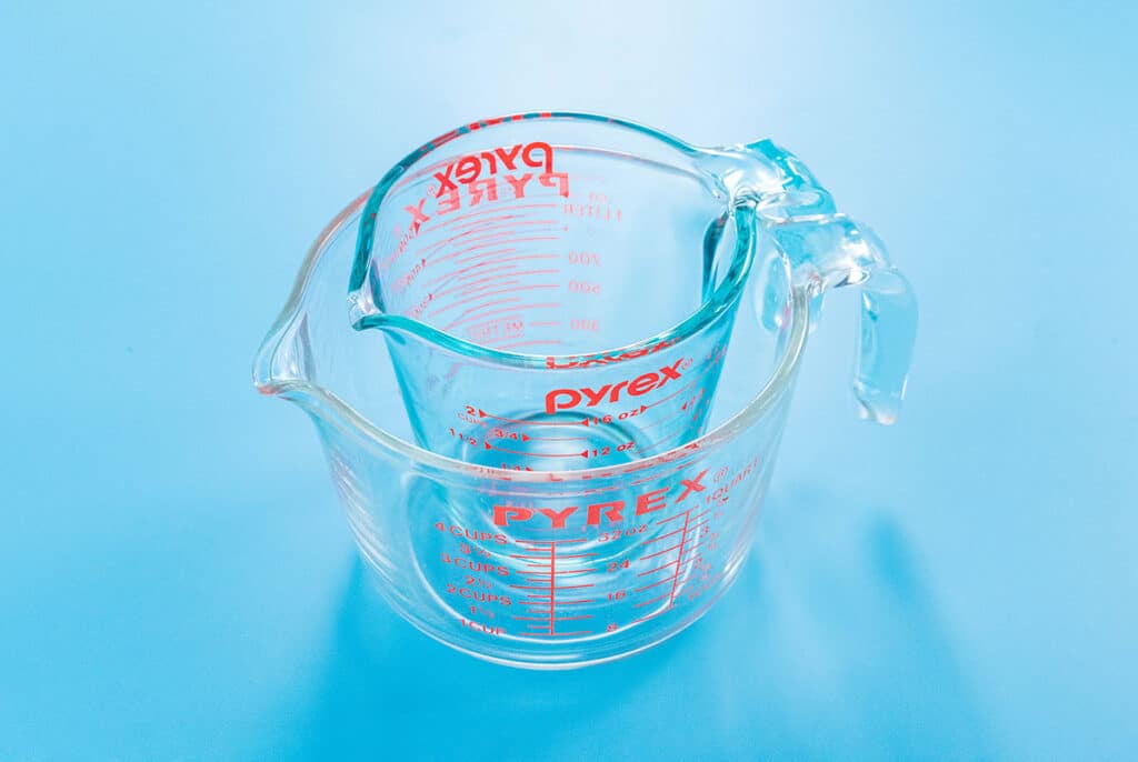 One Pyrex ounce measuring glass resting inside a second, larger Pyrex cup measuring glass