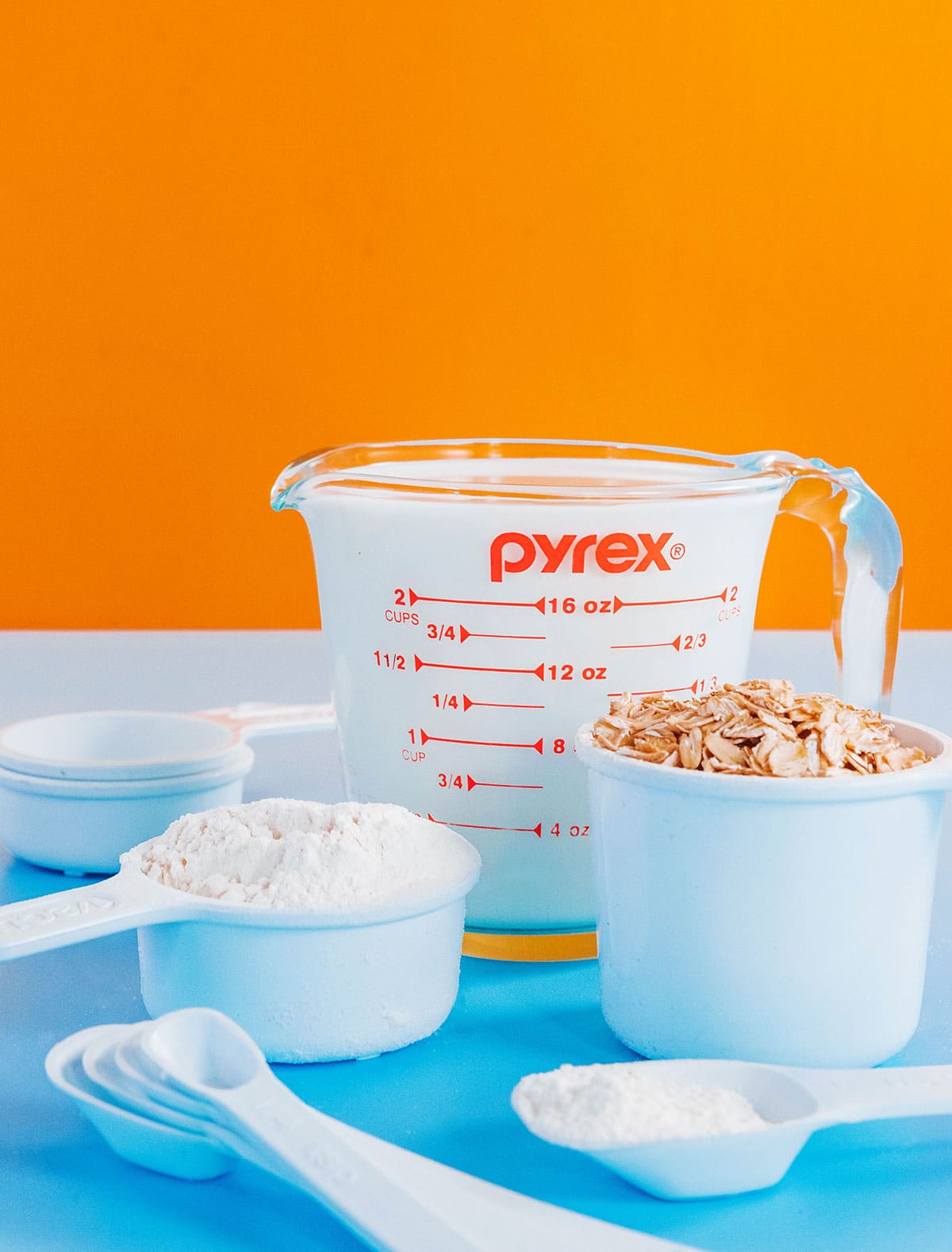 A picture of various measurement utensils, including a glass Pyrex liquid measurement cup and cups full of oats and flour.