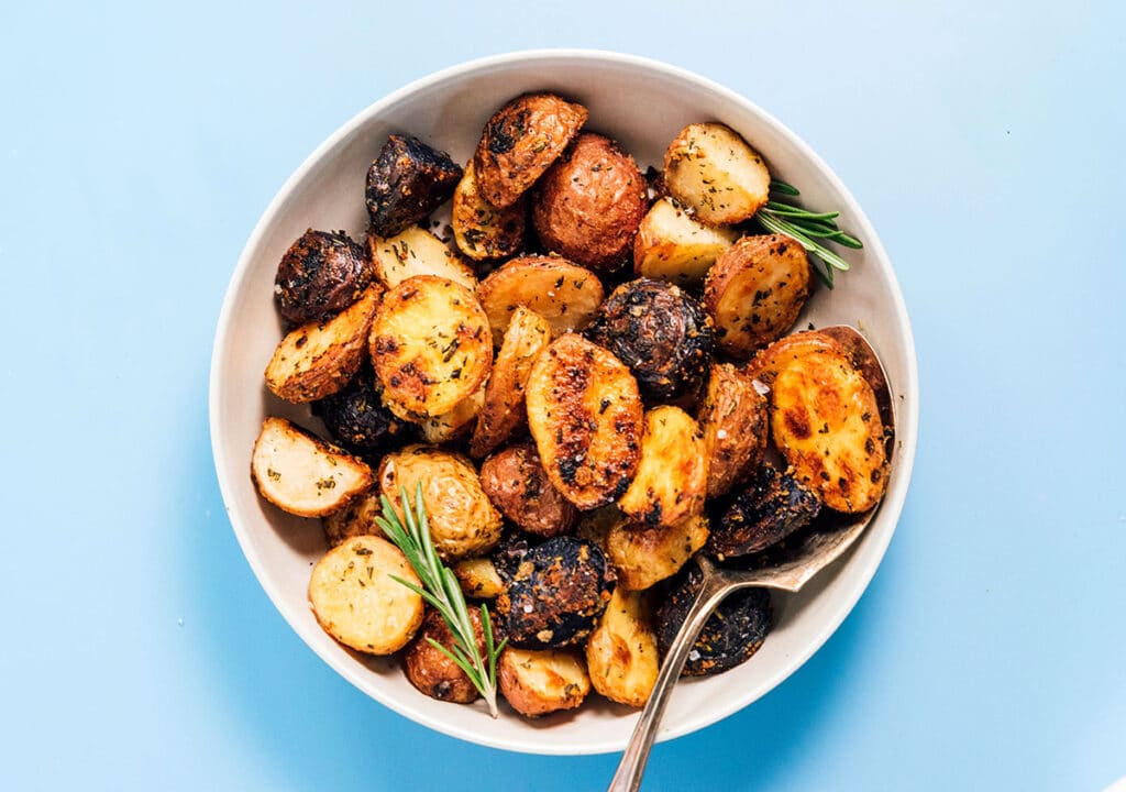 A white bowl filled with roasted potatoes with rosemary