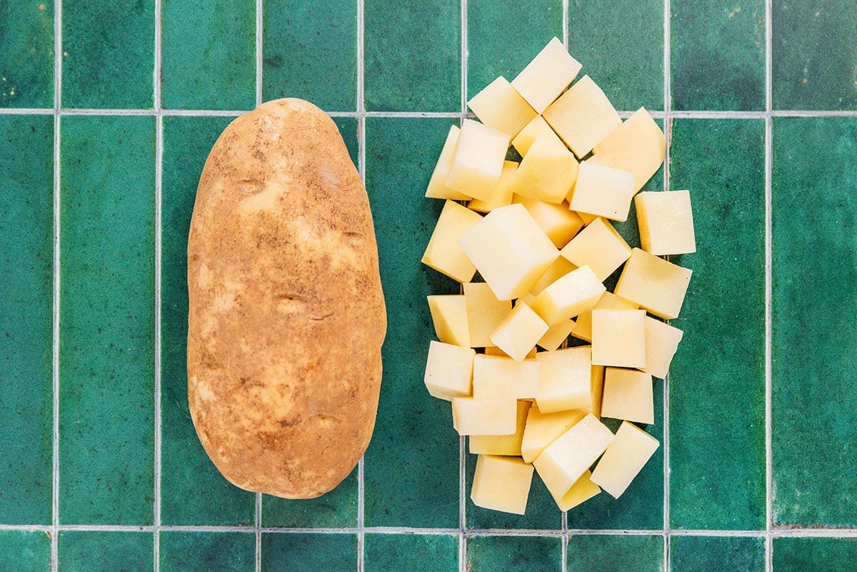 Two russet potatoes side by side, one whole and one diced into cubes