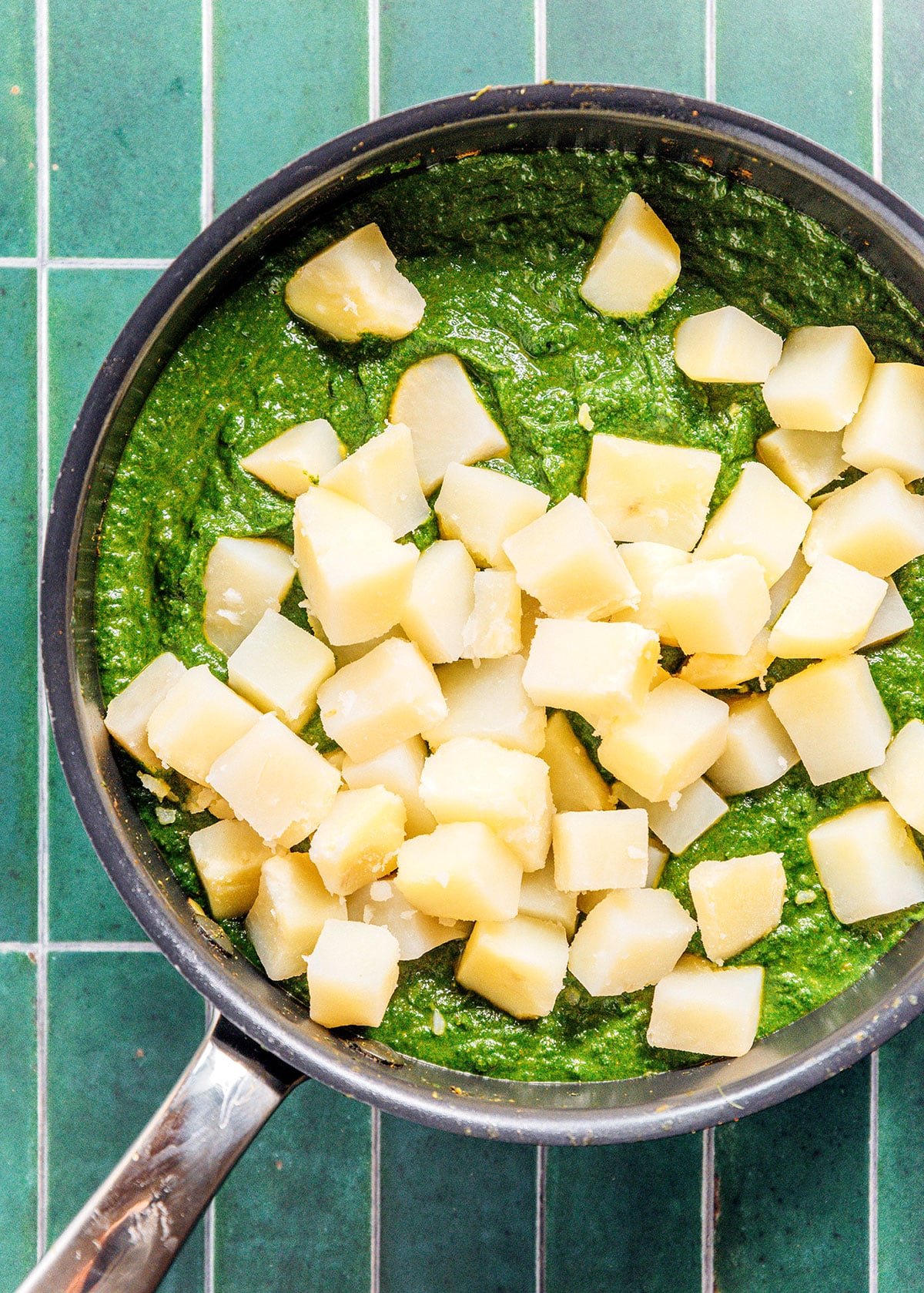 A pot filled with saag aloo green sauce and cubed russet potato