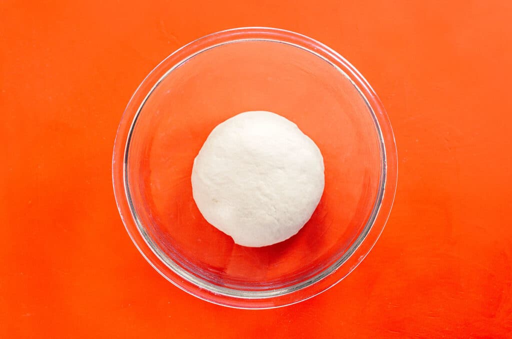 A clear glass bowl filled with unrisen bao bun dough