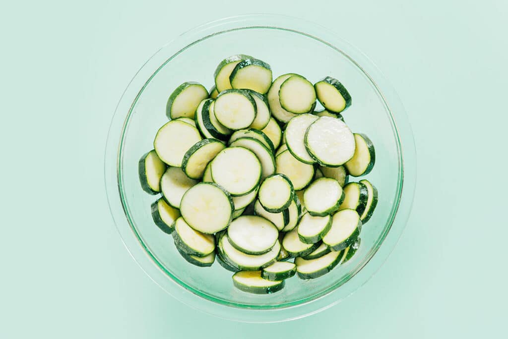 Zucchini rounds in a clear glass mixing bowl.