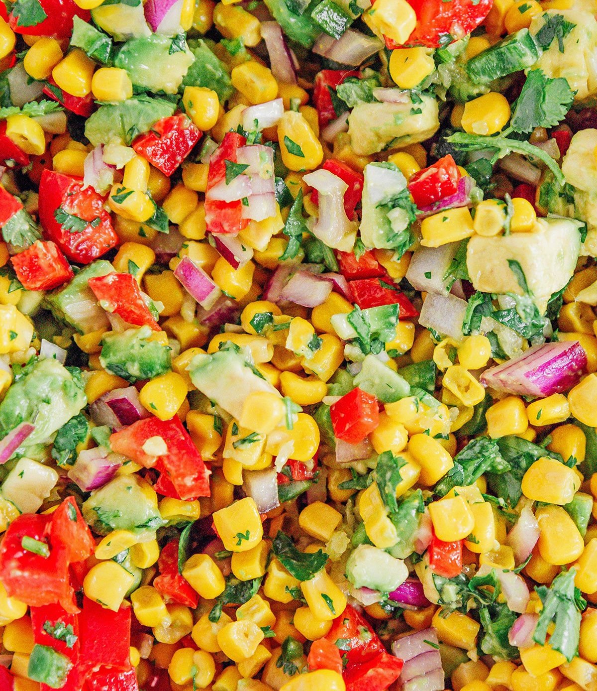 Close up of avocado corn salsa with red onions and bell peppers.