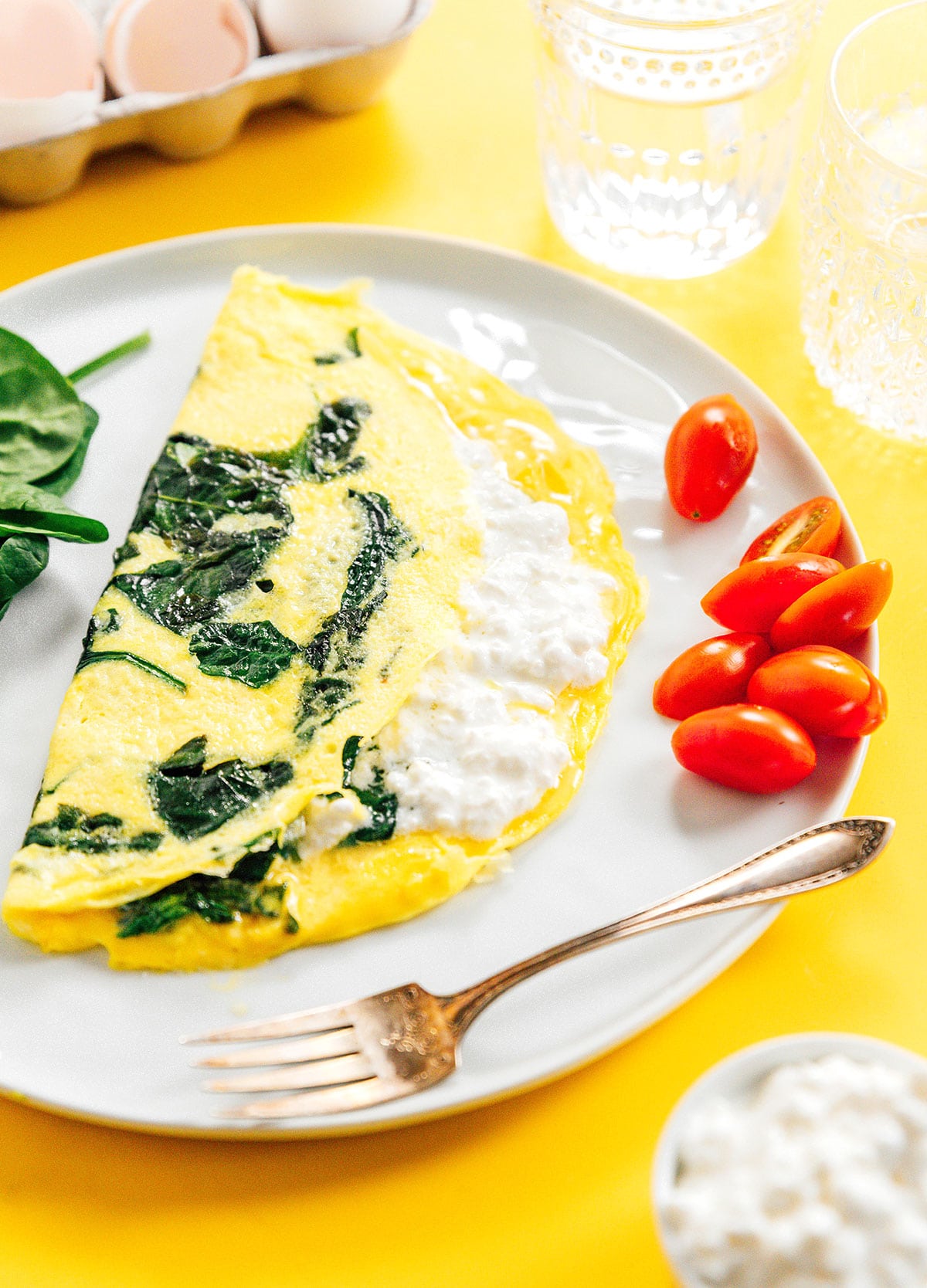 A cottage cheese and spinach omelette on a plate with cherry tomatoes.