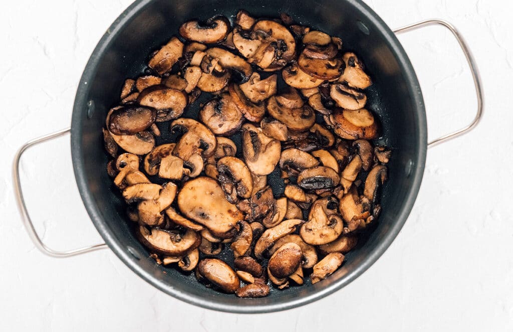 A cooking pot filled with cooked mushrooms