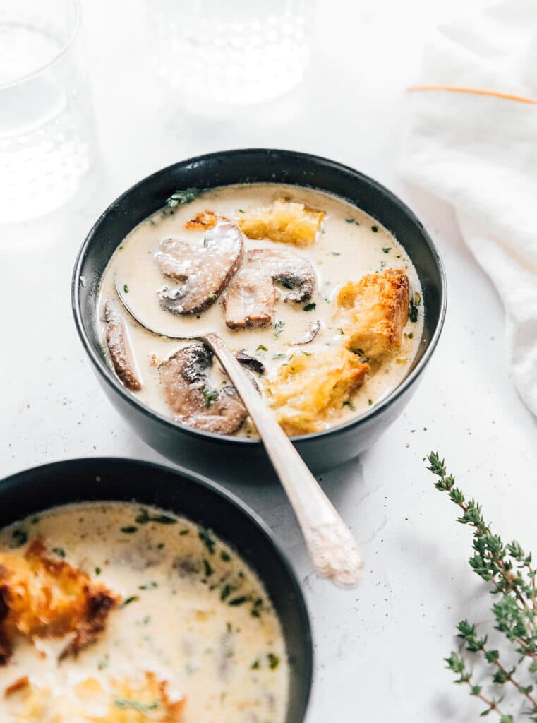 A black bowl filled with vegan creamy mushroom soup