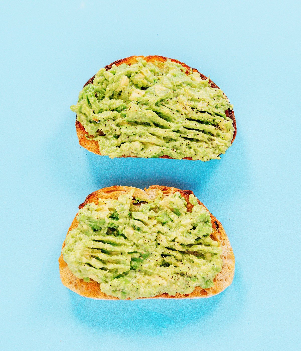 The classic toast with two pieces of toast topped with mashed avocado and lemon juice.