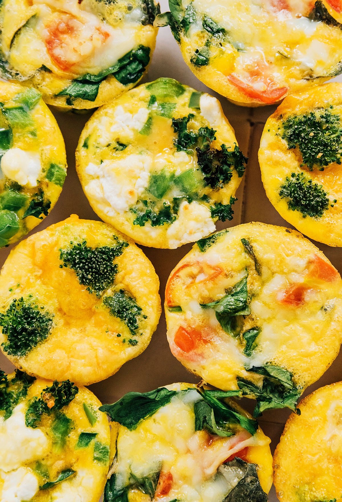 Individual egg cups made with veggies such as broccoli, spinach, and tomato.