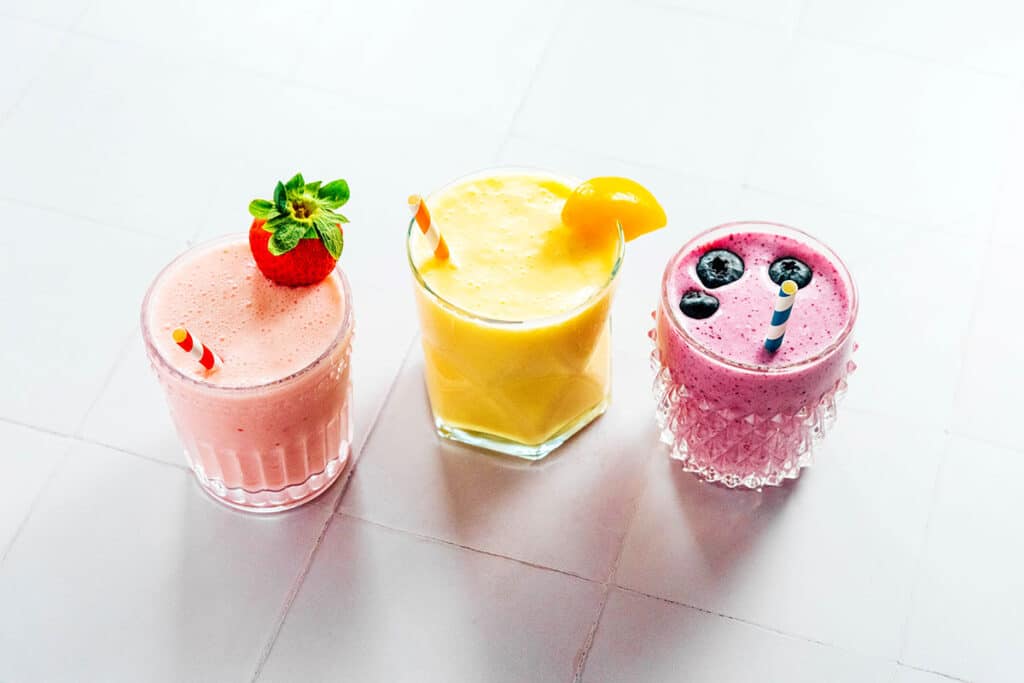 Three glasses filled with strawberry, peach, and blueberry kefir.