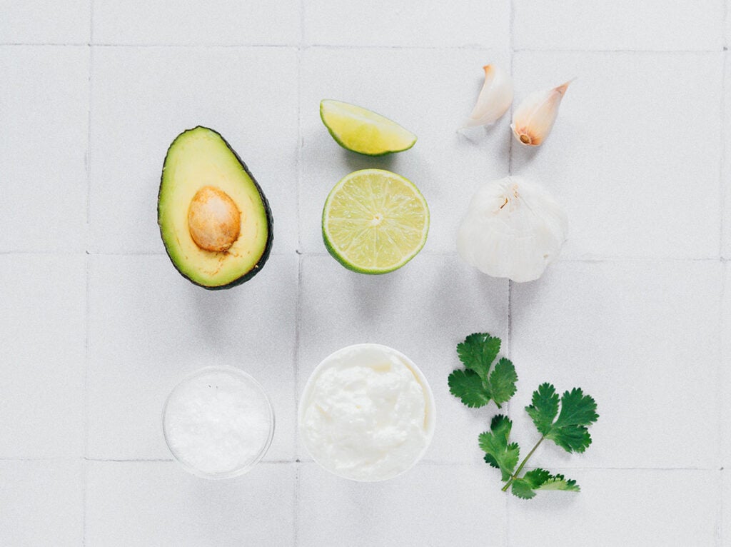 Ingredients for avocado crema on a white surface.