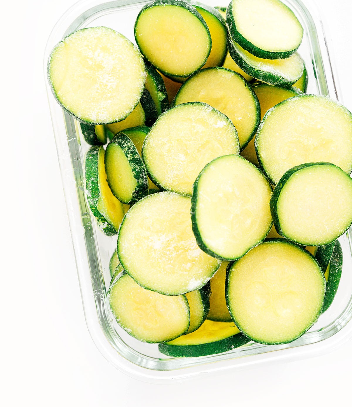 Ice zucchini rounds in a small glass storage container.